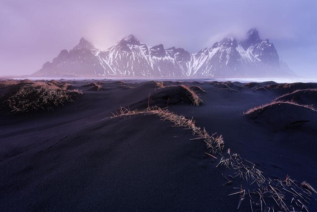 Dunes de sable noir et montagnes enneigées