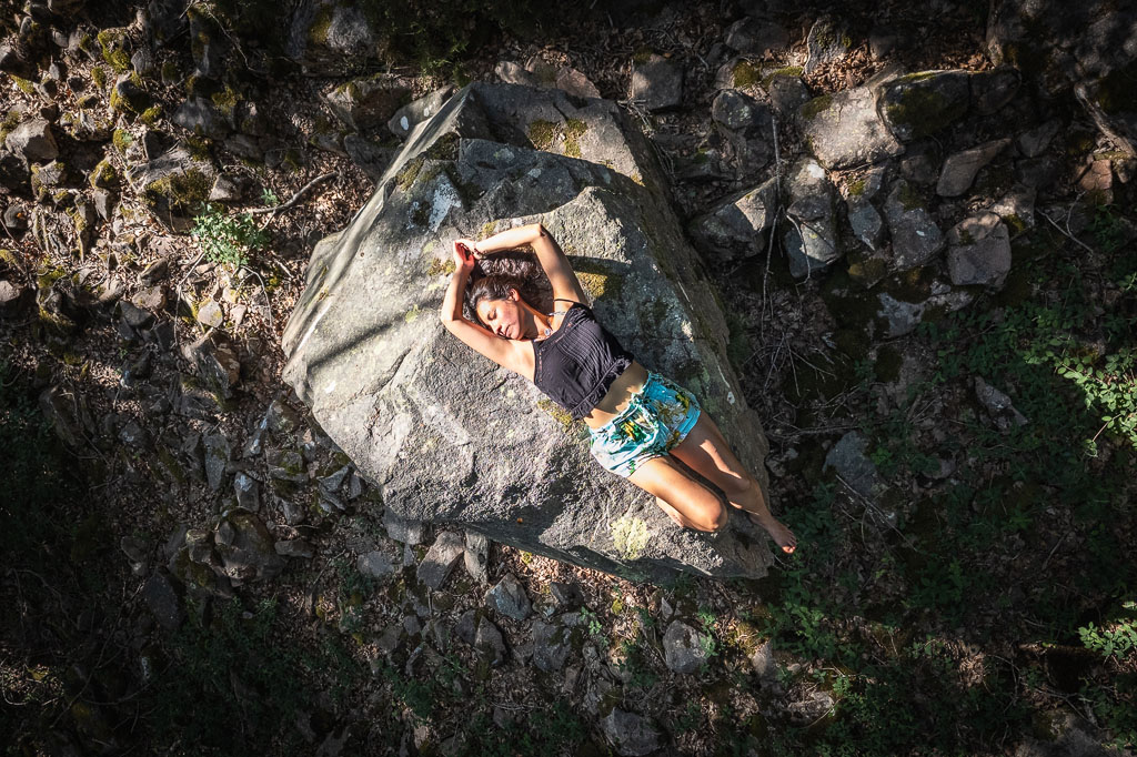 Femme étendue sur un rocher au cœur de la forêt